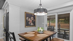Ein Esszimmer mit Holztisch, schwarzen Stühlen, einer Chandelierleuchtre und einem Gemälde an der Wand.