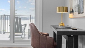 A modern office chair, a desk with a lamp, and a view through a large window.