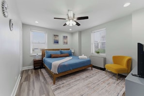 A bedroom with a bed, nightstand, chair, and ceiling fan. - Cityview Peach Centrally Located (Atlanta)