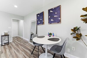 A dining area with a round table, two chairs, and two abstract paintings on the wall. - Cityview Peach Centrally Located (Atlanta)