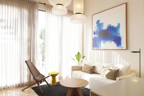 A modern living room with a sofa, a chair, a round table, and a large abstract painting. - Designer New Apt w/ private Rooftop/Old city (Cartagena de Indias)