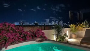 Una piscina en la azotea con vista al horizonte de la ciudad de noche.