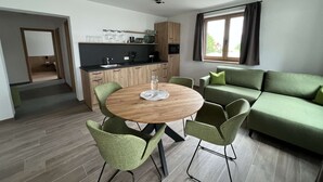 A modern living room with a round wooden table, green chairs, and a green sofa. - Studler-Eck - Holidays at the most beautiful place in the Tyrol (Oberperfuss)