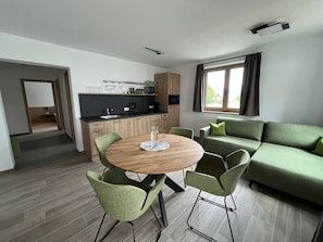 A modern living room with a round wooden table, green chairs, and a green sofa. - Studler-Eck - Holidays at the most beautiful place in the Tyrol (Oberperfuss)