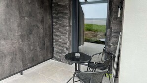 A modern outdoor seating area with a glass door leading to a patio, featuring a stone wall and a view of the outdoors. - Studler-Eck - Holidays at the most beautiful place in the Tyrol (Oberperfuss)