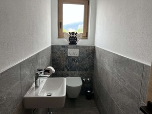 Ein Badezimmer mit Waschbecken, Toilette und einem Fenster mit Ausblick.
