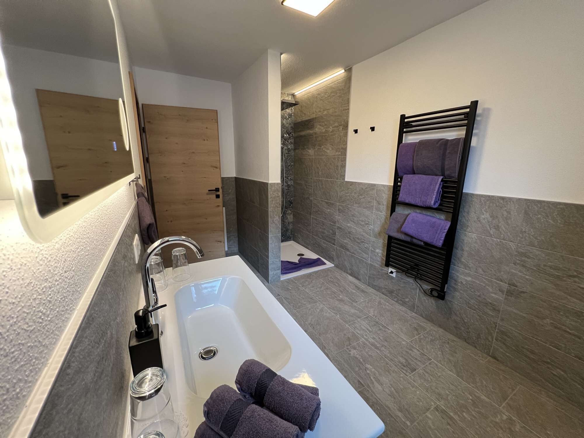 Une salle de bain moderne équipée d’une baignoire, d’un espace douche et d’un porte-serviettes.