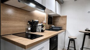 A modern kitchen with a wooden countertop, a built-in stove, and a black dishwasher. - Le Nid Vaillant - Near the Train Station & Free Parking (Tours)