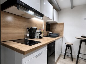 Uma cozinha moderna com bancada de madeira, fogão embutido e lava-louças preta.