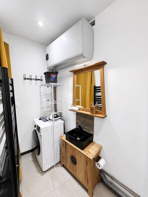 Ein kleiner Hauswirtschaftsraum mit Waschmaschine, Wäscheständer, Spüle und Spiegel.