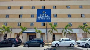 Edifício de um hotel com vários andares e uma placa com a inscrição 'Hotel Aconchego Cearense'.