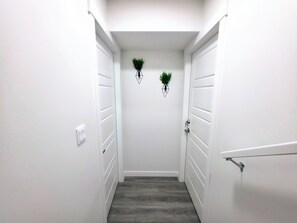 A narrow hallway with white walls and a wooden floor, leading to two white doors. - Cozy 2 Bedroom Legal Suite/Sleeps 4 (Edmonton)