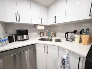 A modern kitchen with white cabinets, stainless steel appliances, and a coffee maker. - Cozy 2 Bedroom Legal Suite/Sleeps 4 (Edmonton)