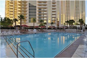 A swimming pool with lounge chairs and umbrellas, surrounded by tall buildings. - Fabulous Signature condo in Tower 1 with beautiful view Las Vegas, No Resort Fee (Las Vegas)