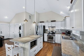 A modern kitchen with white cabinetry, stainless steel appliances, and a marble countertop. - Waterfront & Sunset Views!!  3-bedroom house on Albemarle Sound (Kill Devil Hills)