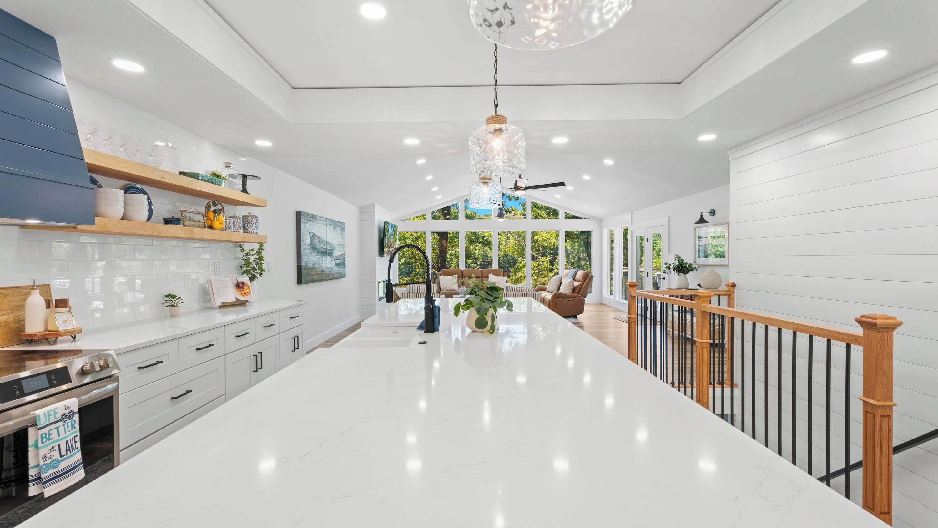 A spacious kitchen with a central island, white cabinetry, and a modern chandelier.