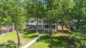 A two-story house with a covered porch, surrounded by trees and a pathway. - The Ozark Acre 6bdr Lakefront (Sunrise Beach)