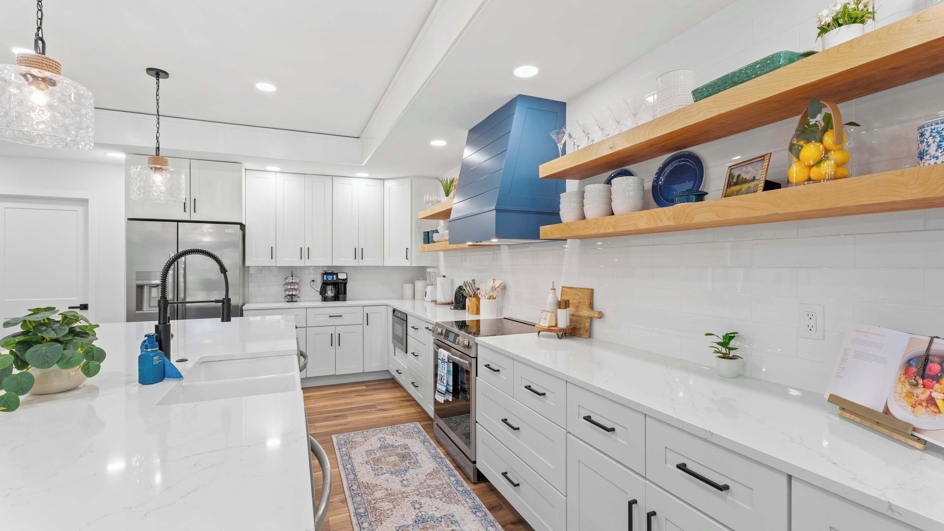 Una cocina moderna con armarios blancos, una isla central y una pared de acento azul.