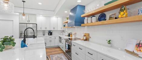 Una cocina moderna con armarios blancos, una isla central y una pared de acento azul.