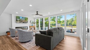 Ein geräumiges Wohnzimmer mit Kamin, großen Fenstern und Seeblick.