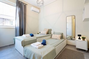 A hotel room with two beds, a large mirror, a small bedside table, and a window with curtains. - Seaside Retreat for Relaxed Kalamata Beach Stays (Kalamata)