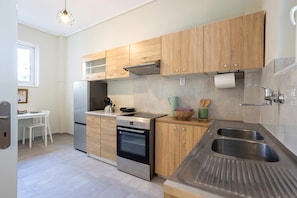 A modern kitchen with wooden cabinets, stainless steel appliances, and a large sink. - Seaside Retreat for Relaxed Kalamata Beach Stays (Kalamata)