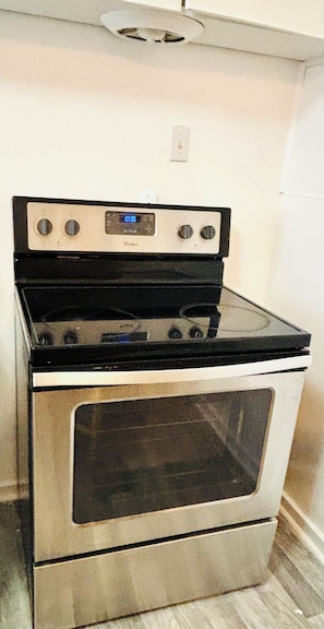A stainless steel oven with a digital control panel, a black stovetop, and a glass oven door.