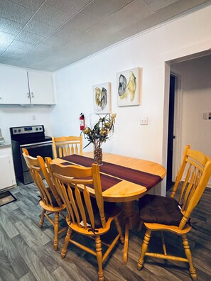 A dining area with a wooden table and chairs, a vase with flowers, and artwork on the wall.
