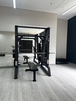 A gym with a squat rack, bench press, and weight plates. - Modern Suite | Santa Fe Clinic | Usaquén (Bogotá)