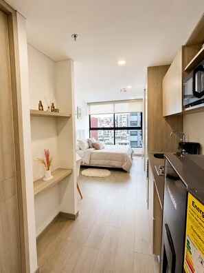 Un apartamento moderno con kitchenette, cama con vista y una pequeña sala de estar.