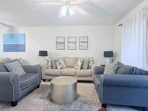 Ein Wohnzimmer mit einer Sofagarnitur, einem Couchtisch und einem Deckenventilator.