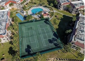 Eine Luftaufnahme einer Wohngegend mit Tennisplatz, Schwimmbad und umliegenden Gebäuden.