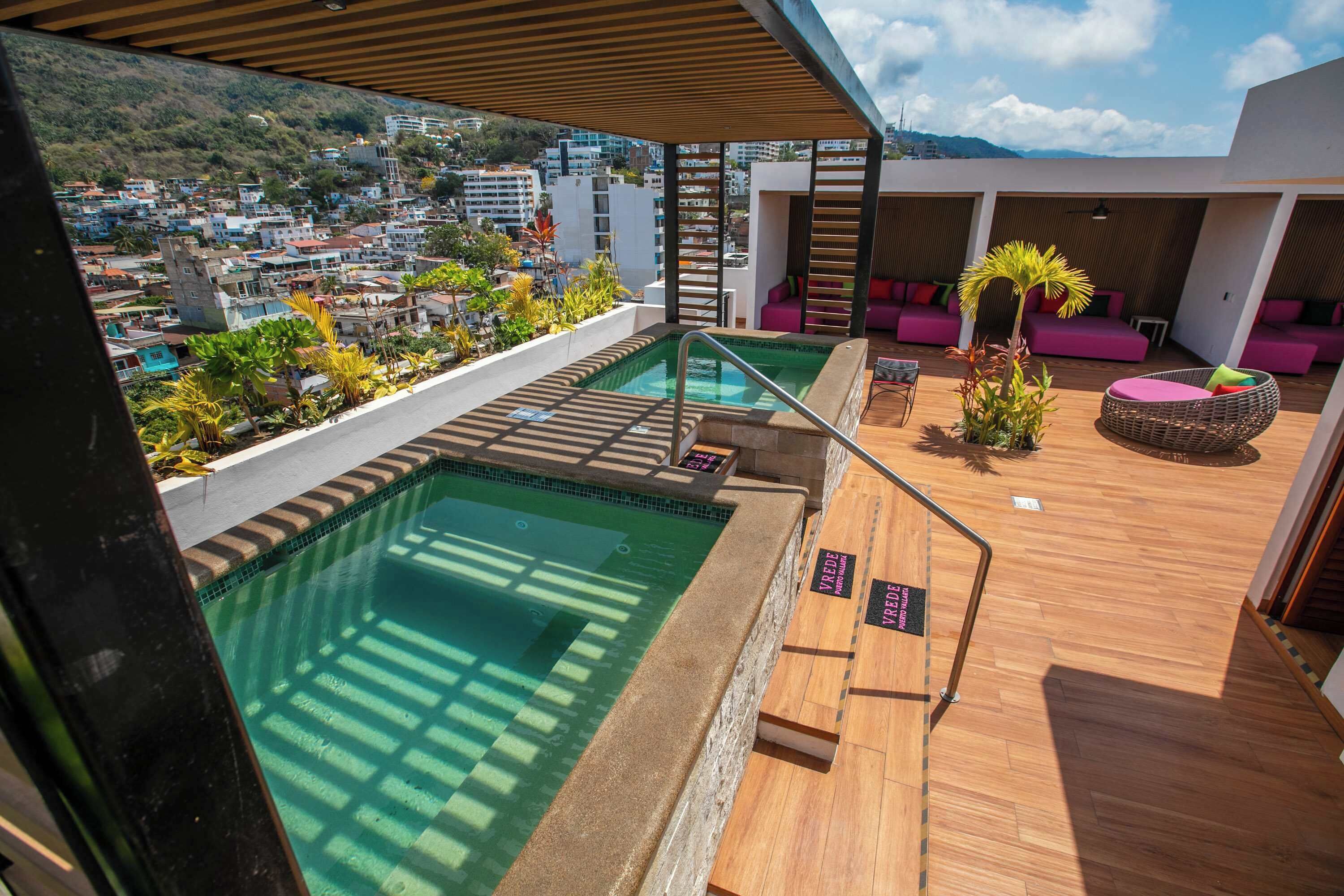 Una piscina sul tetto con vista sulla città, terrazza in legno e area relax.