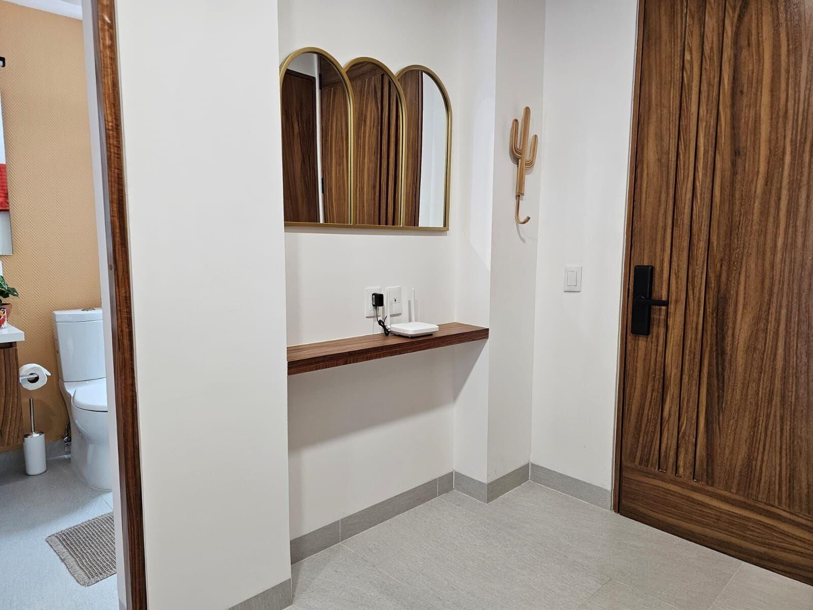 Ein Badezimmer mit einem Holzkosmetikschrank, einem Spiegel, einer Toilette und einer Tür.