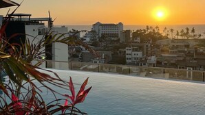 En infinitypool med utsikt över solnedgången över en stadssiluett.