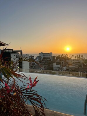 An infinity pool with a view of the sunset over a cityscape. - Casa Lluvia Retreat • Rooftop Infinity Pool (Puerto Vallarta)