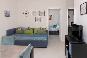 A modern living room with a sofa, a TV, and a dining area. - Unit 8 - Bright Apartment Near the Beach & Downtown (Piano di Sorrento)