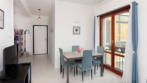 Ein moderner Essbereich mit Tisch und Stühlen, einem Computerarbeitsplatz und Blick ins Freie durch eine Schiebetür.