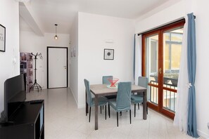A modern dining area with a table and chairs, a computer setup, and a view of the outdoors through a sliding glass door. - Unit 8 - Bright Apartment Near the Beach & Downtown (Piano di Sorrento)