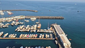 Marina con numerosas embarcaciones amarradas, un muelle y un edificio de techo plano.
