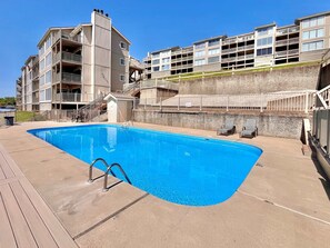 A swimming pool with a metal ladder, adjacent to a multi-story building with balconies and a small shed. - Serenity Pointe Boat Slip (Osage Beach)