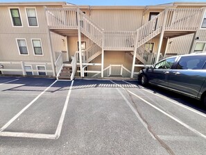 A multi-story building with a parking lot, a staircase, and a car parked in one of the spaces. - Serenity Pointe Boat Slip (Osage Beach)