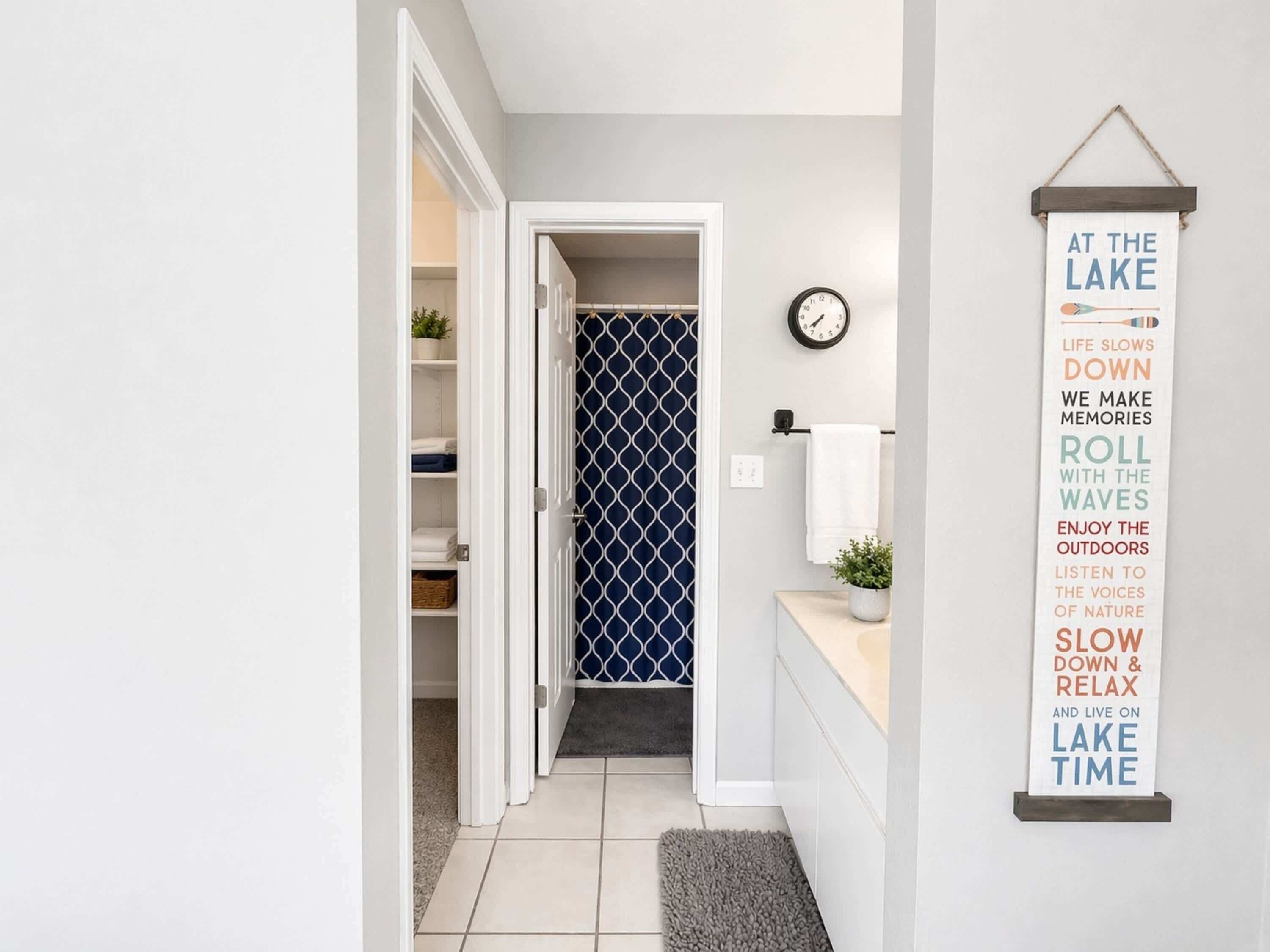 A hallway with a closet, a clock, and a motivational sign.