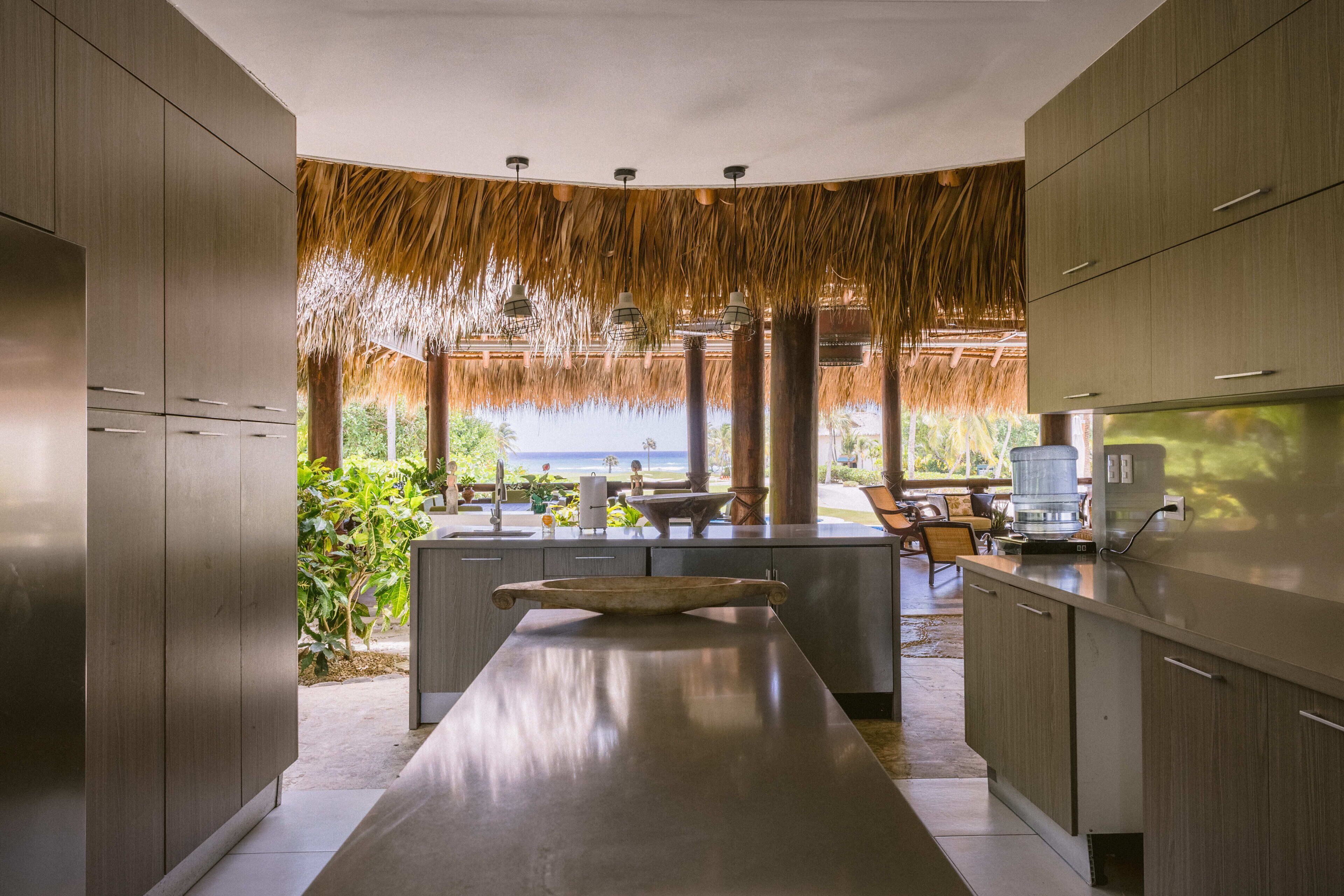 Una cocina moderna con una isla grande, armarios de madera y vista al océano.