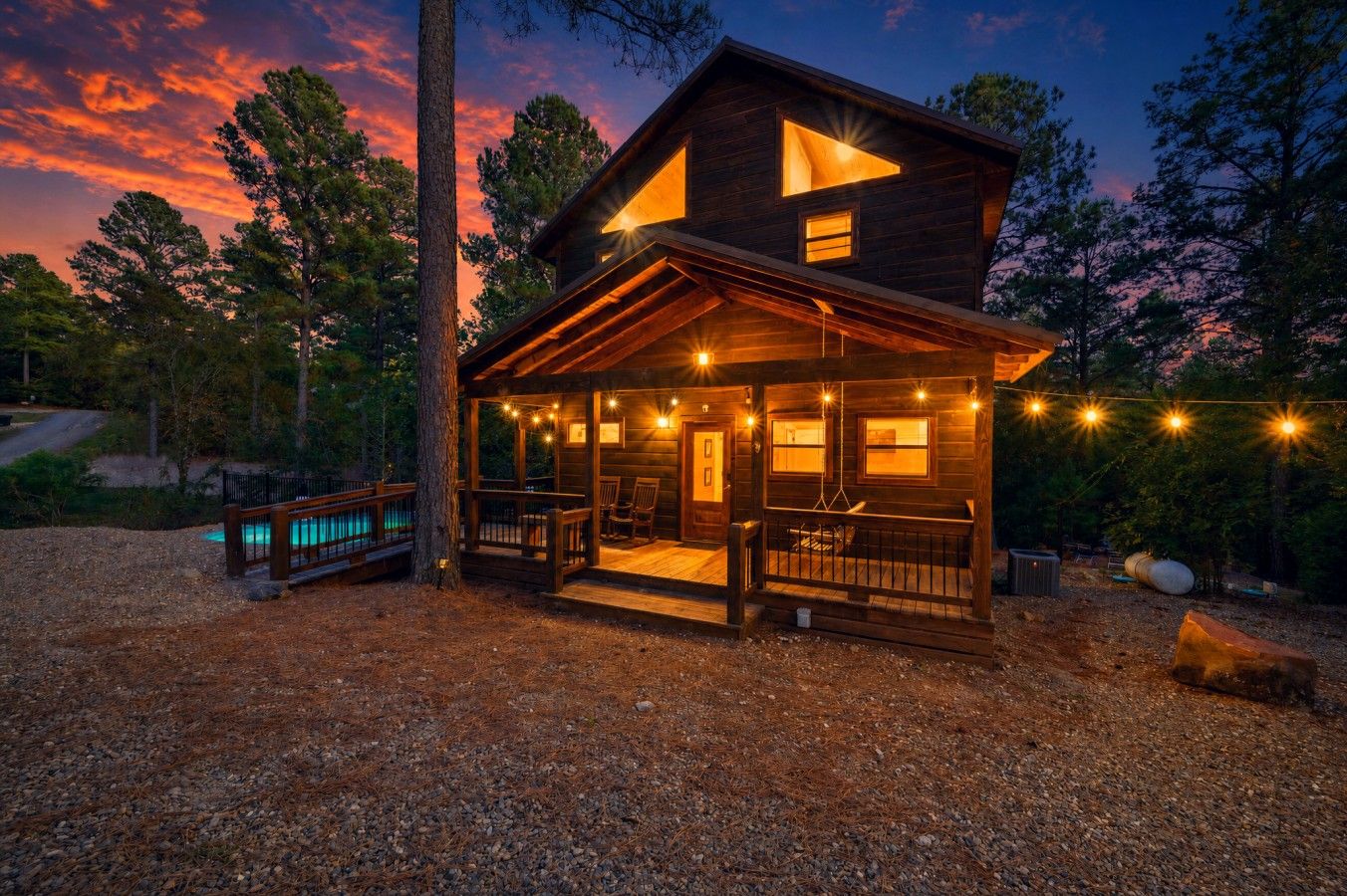 Porch swings, pine trees, a pool, and that sky — this cabin is the whole package.