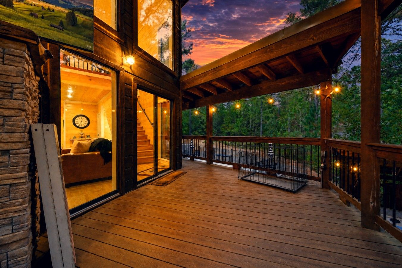 A wooden deck with a view of the landscape, a staircase leading to a room with a clock, and string lights.