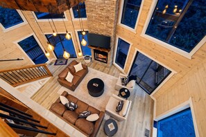 Un salón amplio con chimenea, varias opciones de asientos y ventanas grandes.
