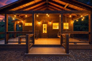 Una cabaña de madera con porche, varias ventanas y luces colgantes.