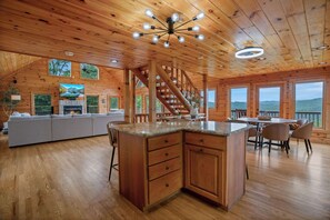 L’intérieur de ce chalet spacieux, construit en bois, comprend une cuisine, un coin repas et un salon. Il est doté de planchers en bois, d’une cheminée et de grandes fenêtres.