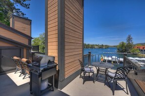 Un patio con una parrilla, sillas y vistas a un lago.